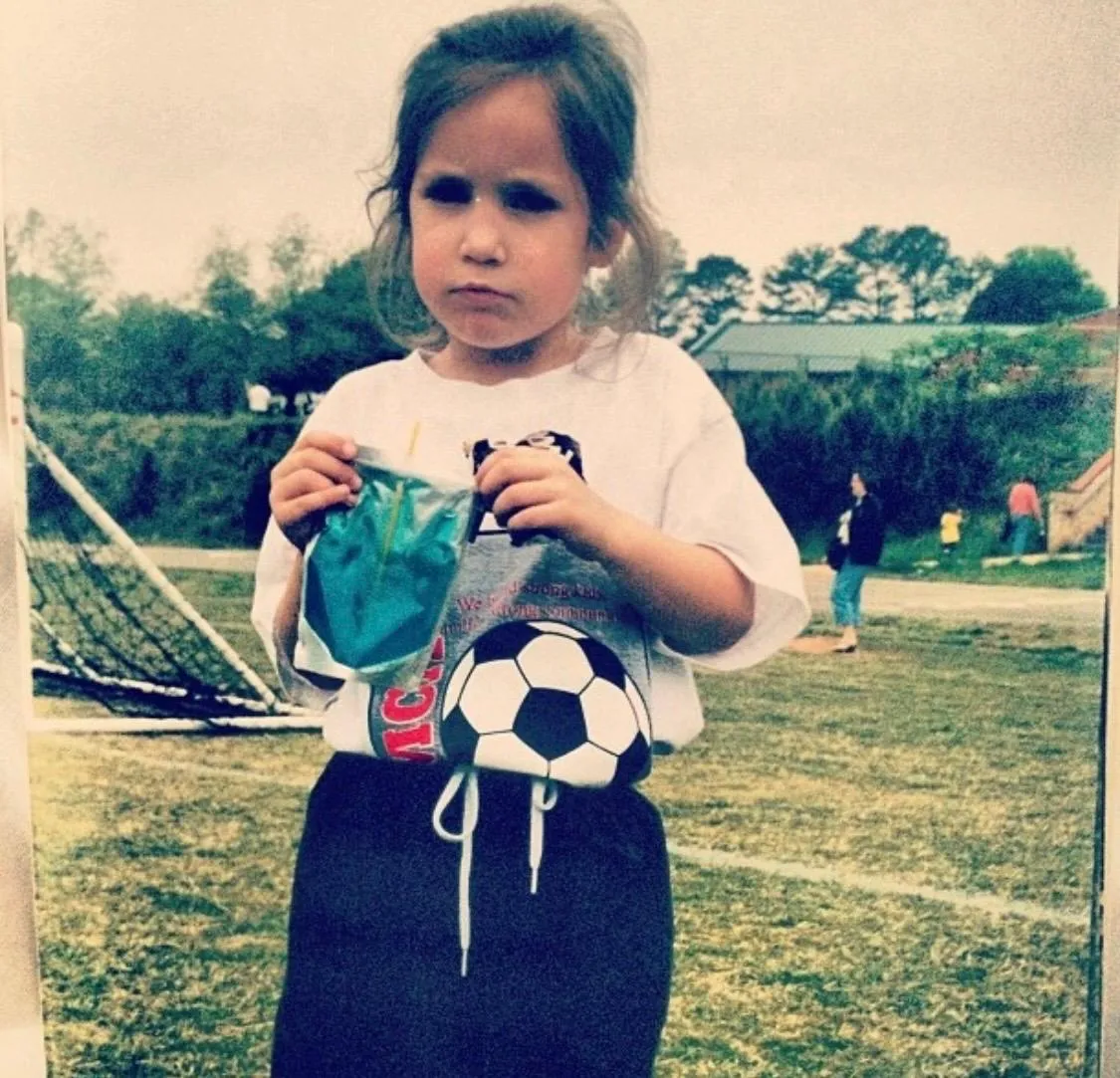 Kelly as a toddler at a YMCA soccer game, drinking a Capri Sun.